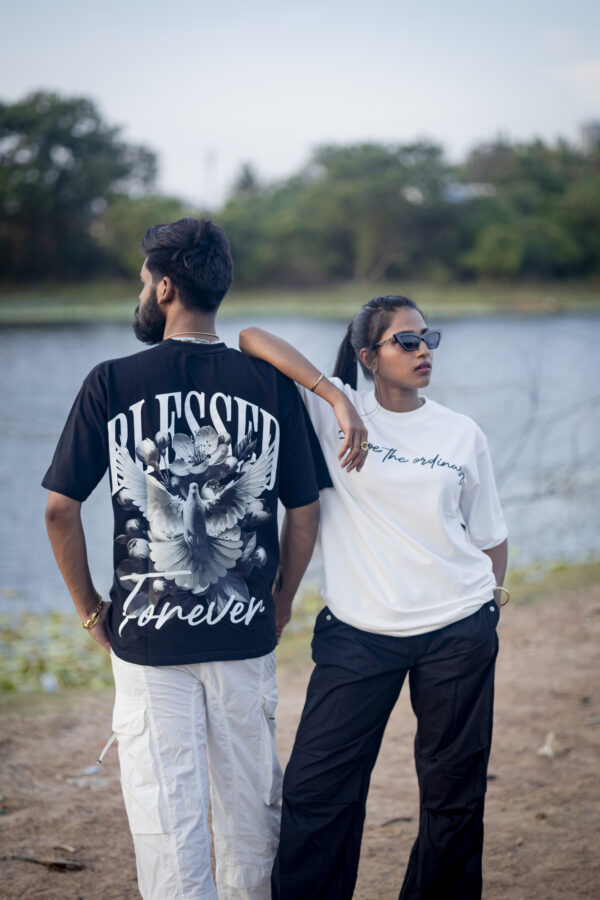 Man and woman wearing trendy streetwear t-shirts with bold prints standing by a lakeside, showcasing urban fashion style.