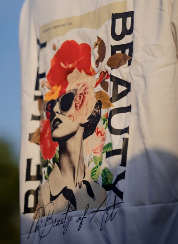 Close-up of a vibrant graphic on the back of a T-shirt showcasing a woman's face, large flowers, and the text The Beauty of Art.